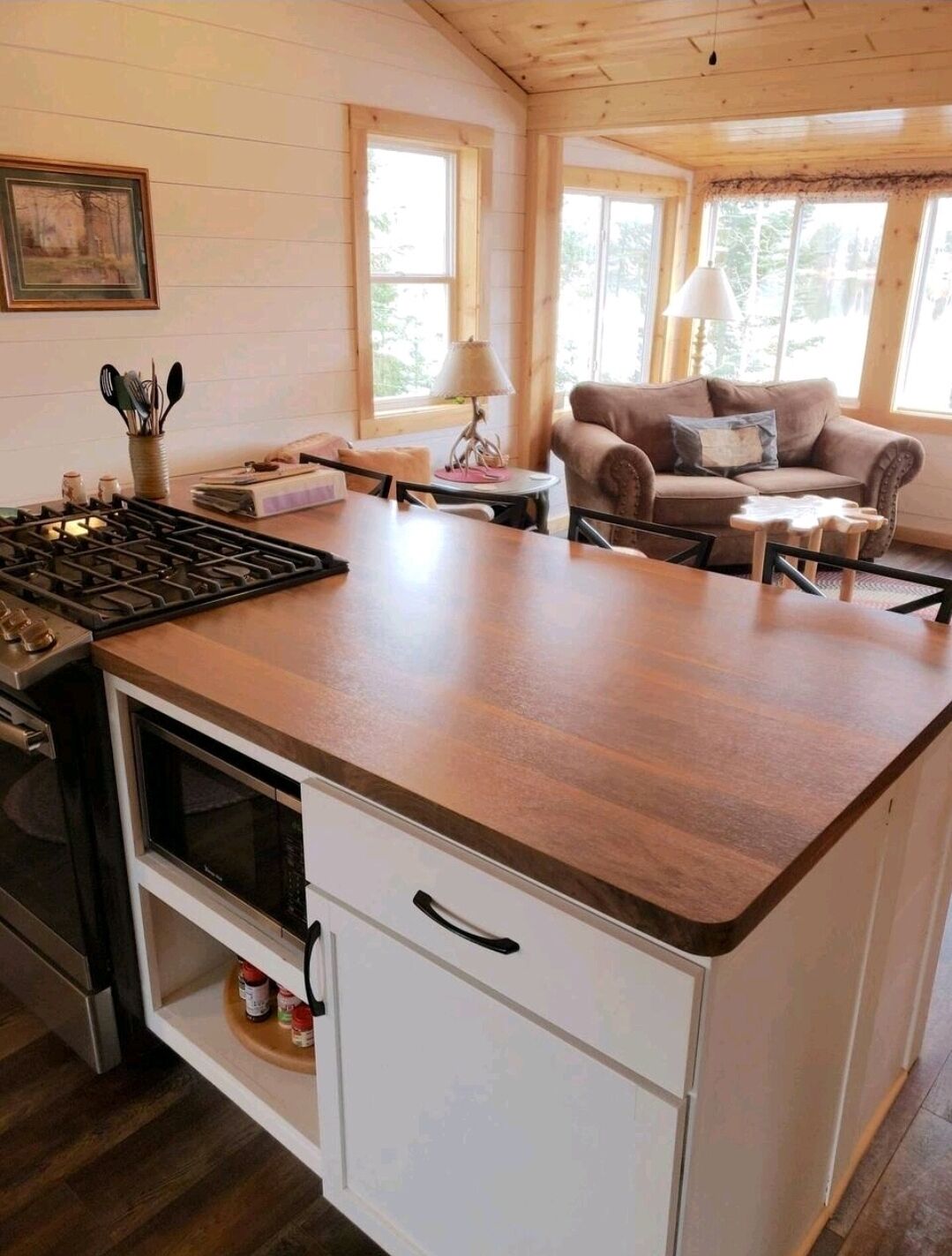 A cozy kitchen with a wooden countertop, a stove, and a dining area with a couch and table.