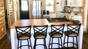 A kitchen with a wooden island, bar stools, and a stainless steel refrigerator.