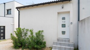 Un edificio con fachada blanca, una puerta con la leyenda 'Guest House' y un pequeño conjunto de escalones que conducen a la entrada.