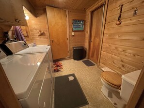 Et badeværelse i en træhytte med badekar, toilet og en lille skraldespand.