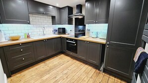 A modern kitchen with dark cabinets, a wooden countertop, a built-in oven, and a microwave. - Unique town centre apartment with vaulted ceiling - Pass the Keys (Shrewsbury)