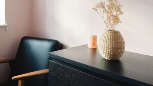 A dark wooden table with a woven vase containing dried flowers and a candle.
