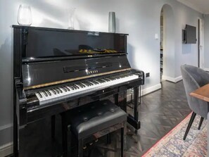 Relax in this stylish living room with a grand piano, comfortable armchair, and flat-screen TV.