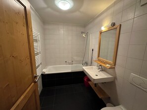 A bathroom with a bathtub, a sink, and a toilet. - Mountain River Resort (Val d'Illiez)