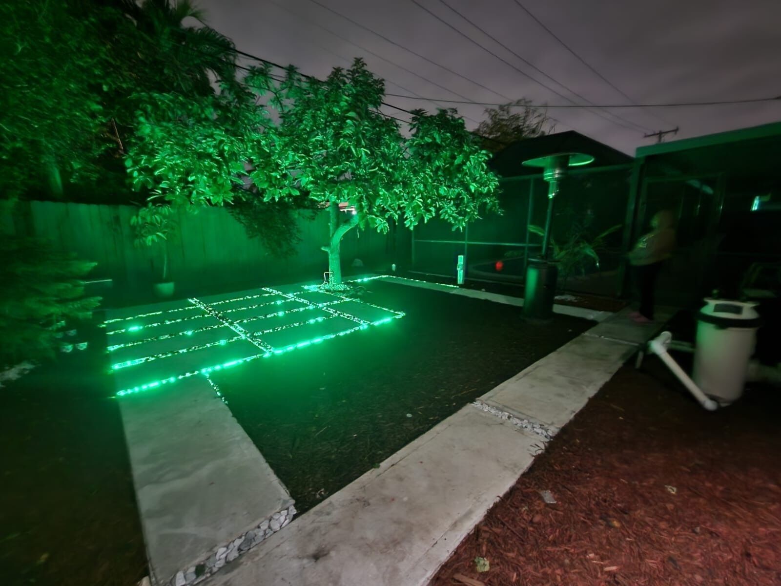 Un espacio al aire libre con pavimento, un árbol y una zona cubierta para sentarse.