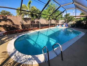 A swimming pool with a covered area, surrounded by trees and a fence. - The Perfect Vacation Getaway ! (Miami)