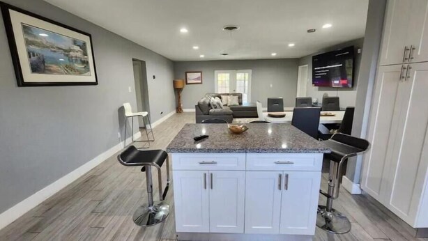 A modern kitchen with a central island, white cabinetry, and a dining area with bar stools. - The Perfect Vacation Getaway ! (Miami)