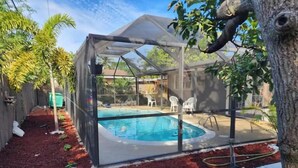 A backyard with a swimming pool, covered patio, and red mulch ground cover. - The Perfect Vacation Getaway ! (Miami)
