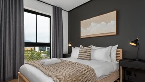 A modern bedroom with a large bed, a view of the city, and a painting on the wall. - Comfort and Style With Stunning Table Mountain View (Cape Town)