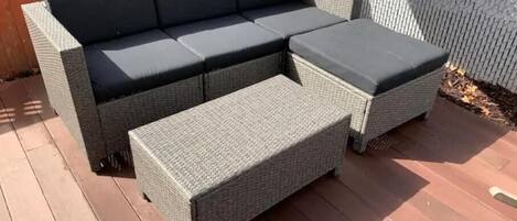 Ein modulares Sofa mit Chaiselongue und Ottomanen auf einer Holzterrasse.