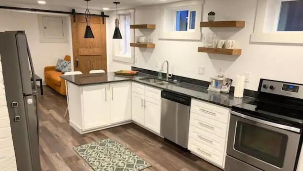 Een moderne keuken met witte kastjes, roestvrijstalen apparatuur en een houten vloer.