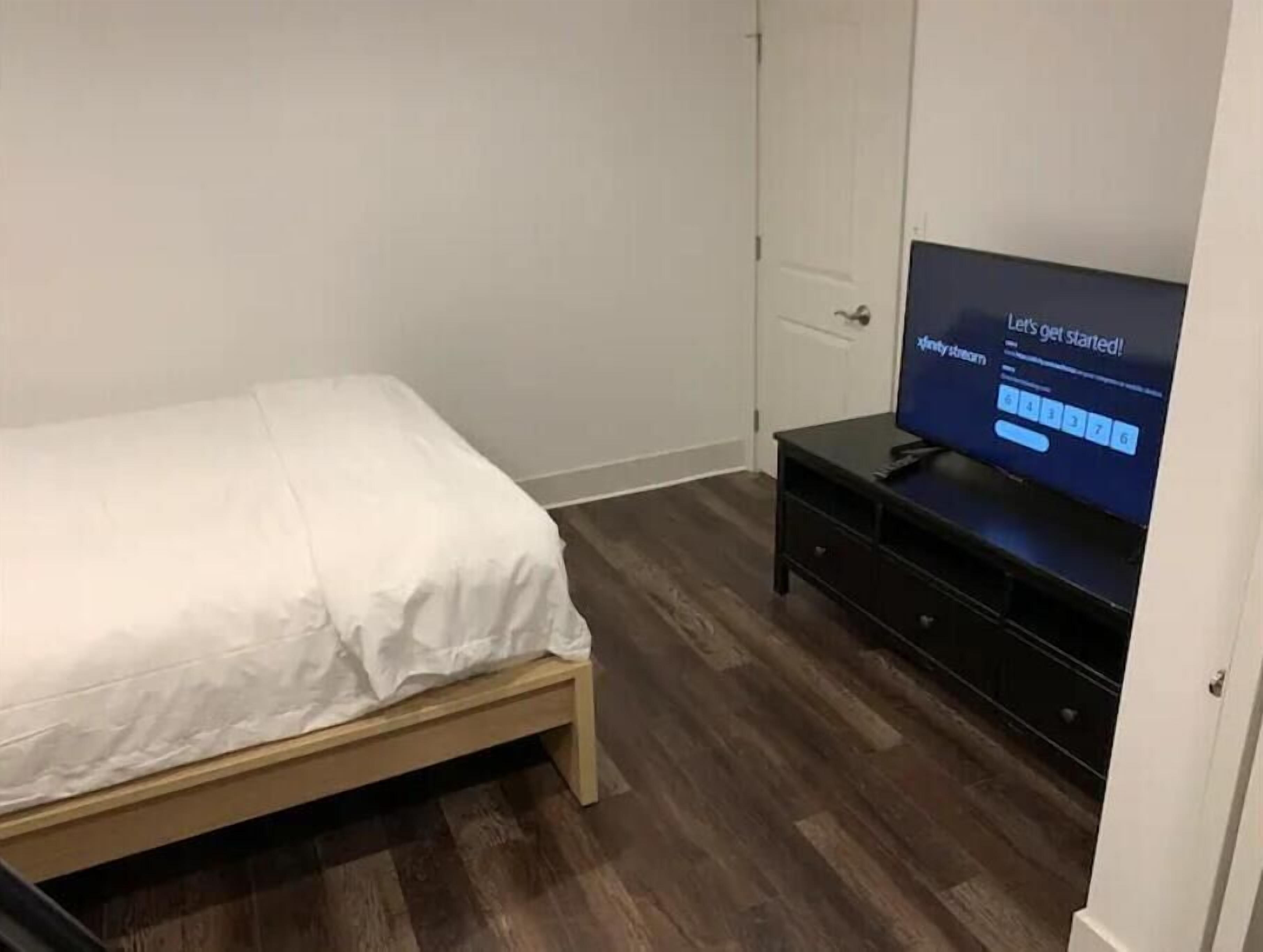 Une chambre à coucher avec un lit, un téléviseur posé sur un meuble et une porte.