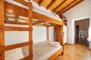 A bunk bed room with a wooden ladder, a small table, and a chair.