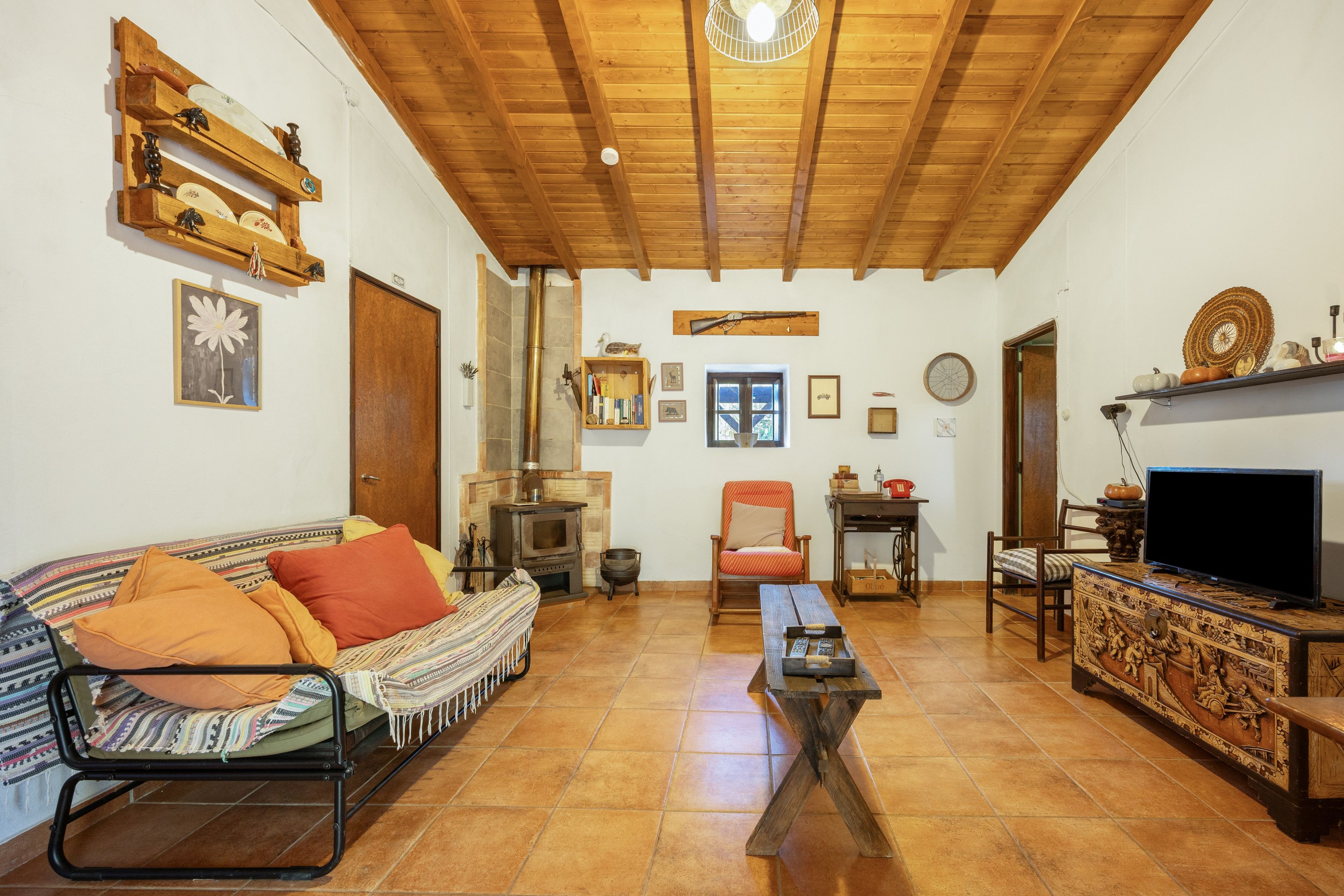 A cozy living room with a fireplace, a sofa, a television, and various decorative items.
