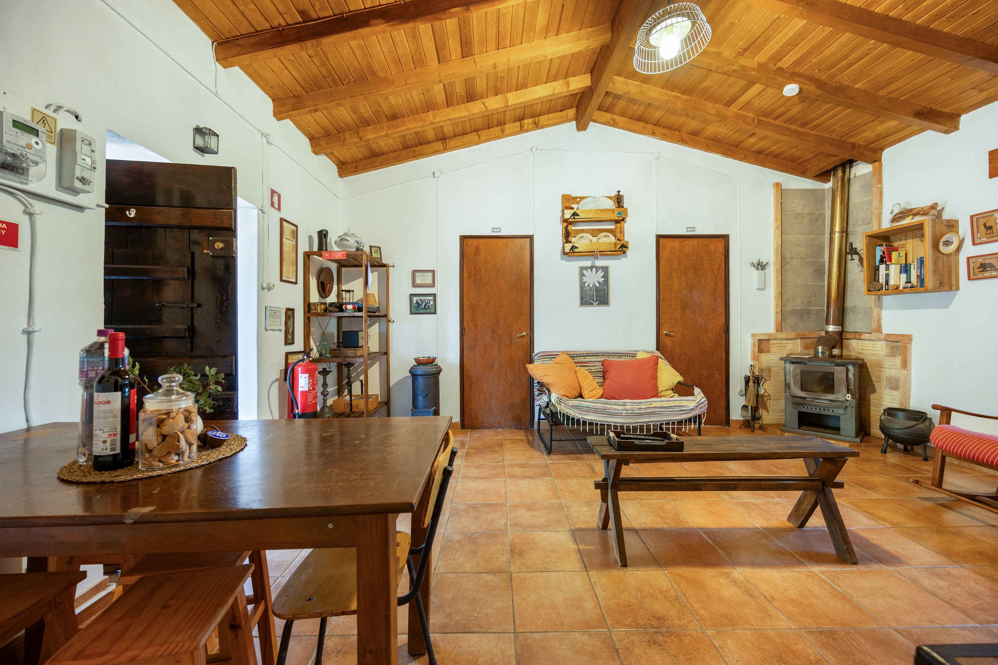 Un'ampia zona giorno con soffitto in legno, un camino e un tavolo da pranzo con sedie.