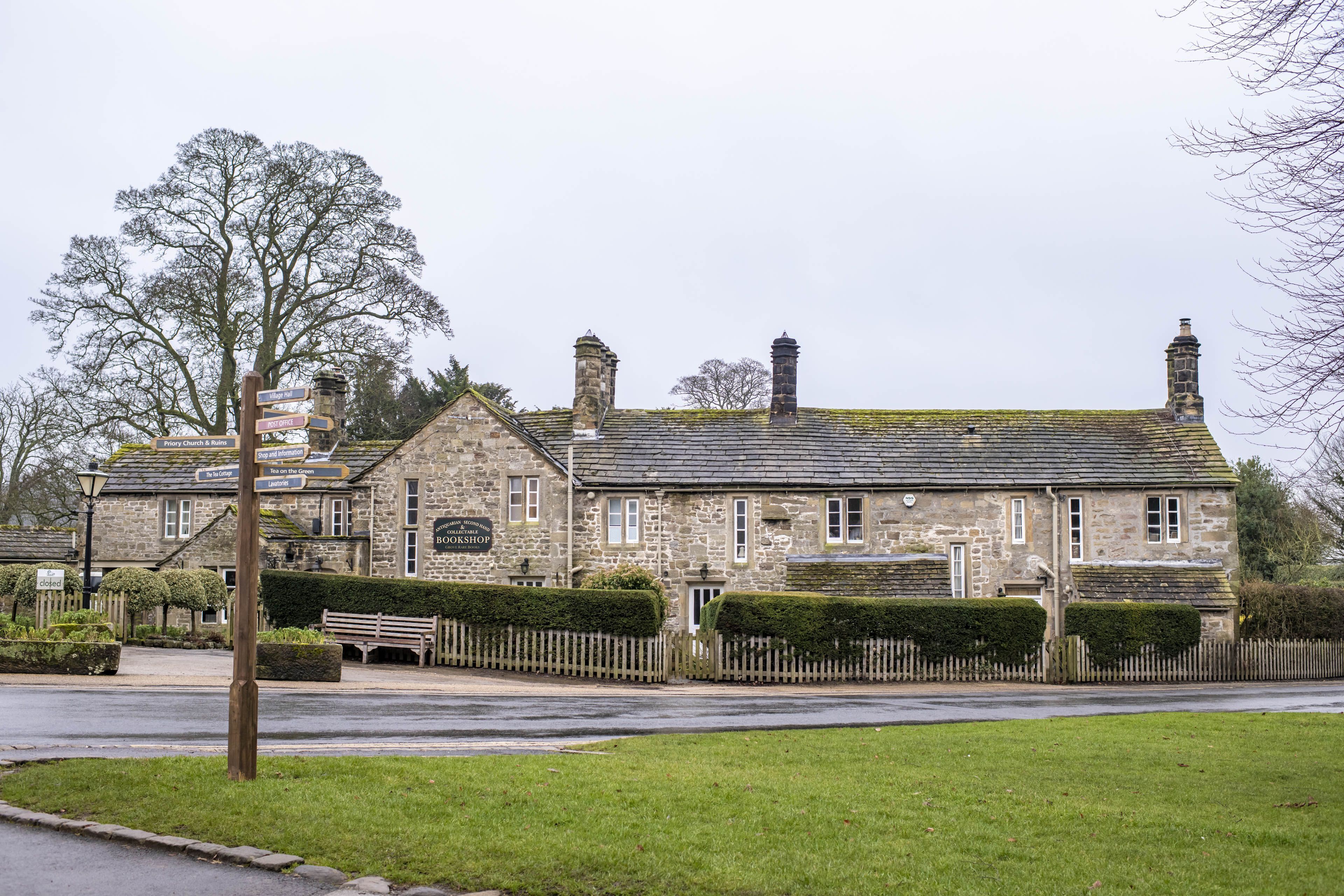 A stone building with a signboard, a bench, and a fence.
