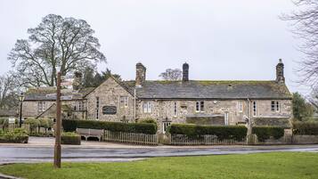 A stone building with a signboard, a bench, and a fence.