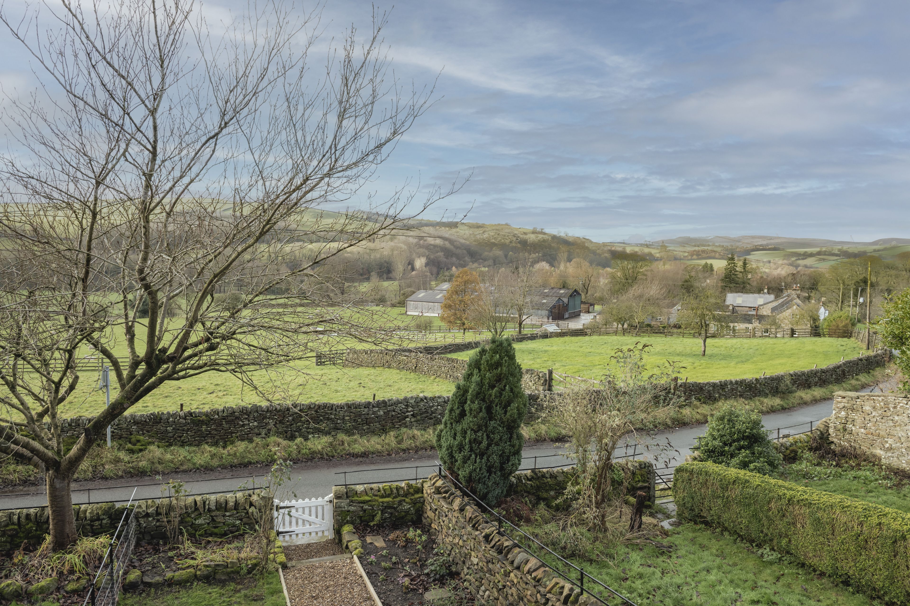 A rural landscape with stone walls, a river, and houses in the distance.
