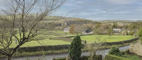 A rural landscape with stone walls, a river, and houses in the distance.