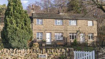 A stone house with a stone wall, a wooden bench, and a sign that reads "Wharf View".