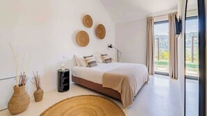 Camera da letto moderna con un ampio letto, un comodino, una lampada e vista sull'esterno.