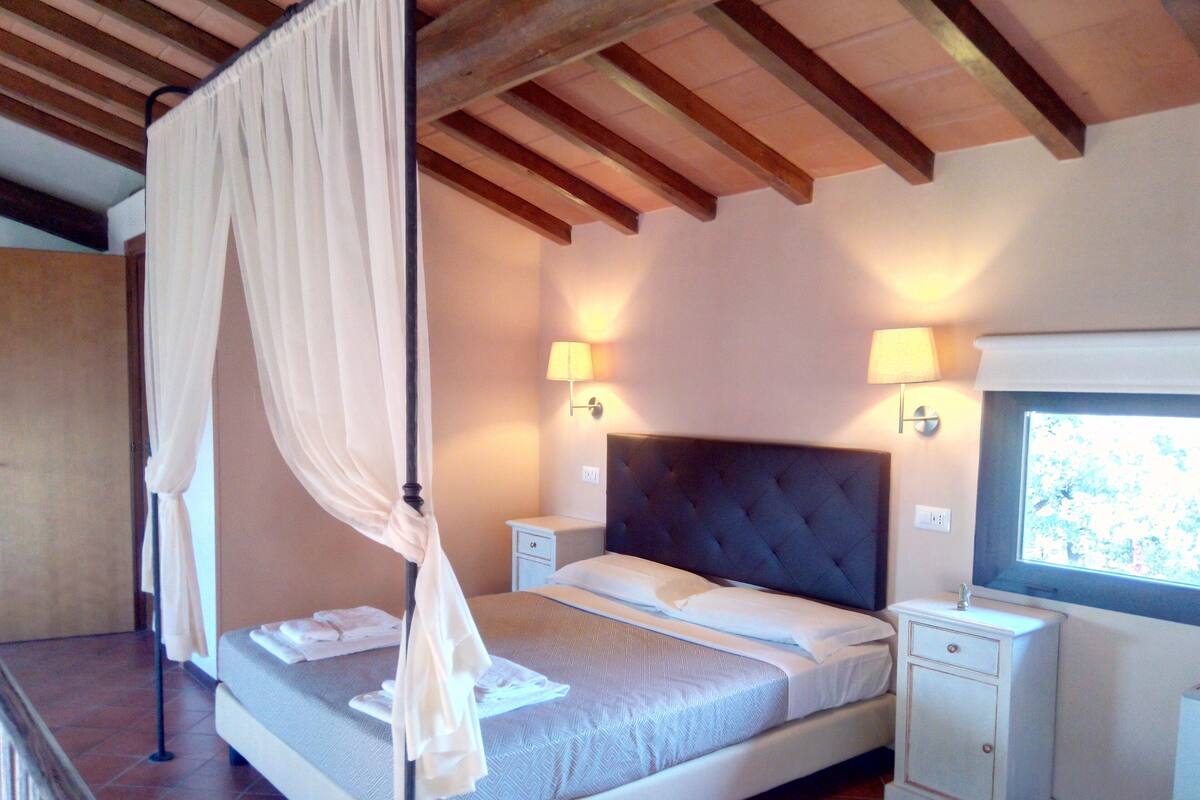 Une chambre à coucher avec un lit, des tables de chevet, une fenêtre et un plafond en bois.