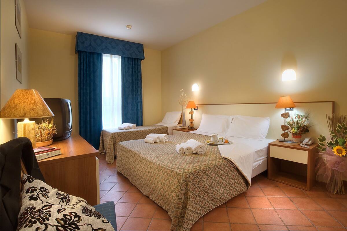 Une chambre d’hôtel avec deux lits, un bureau avec une lampe, une chaise et un téléviseur.