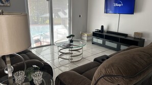 Un salon moderne avec un téléviseur à écran plat, une table basse en verre et un canapé.
