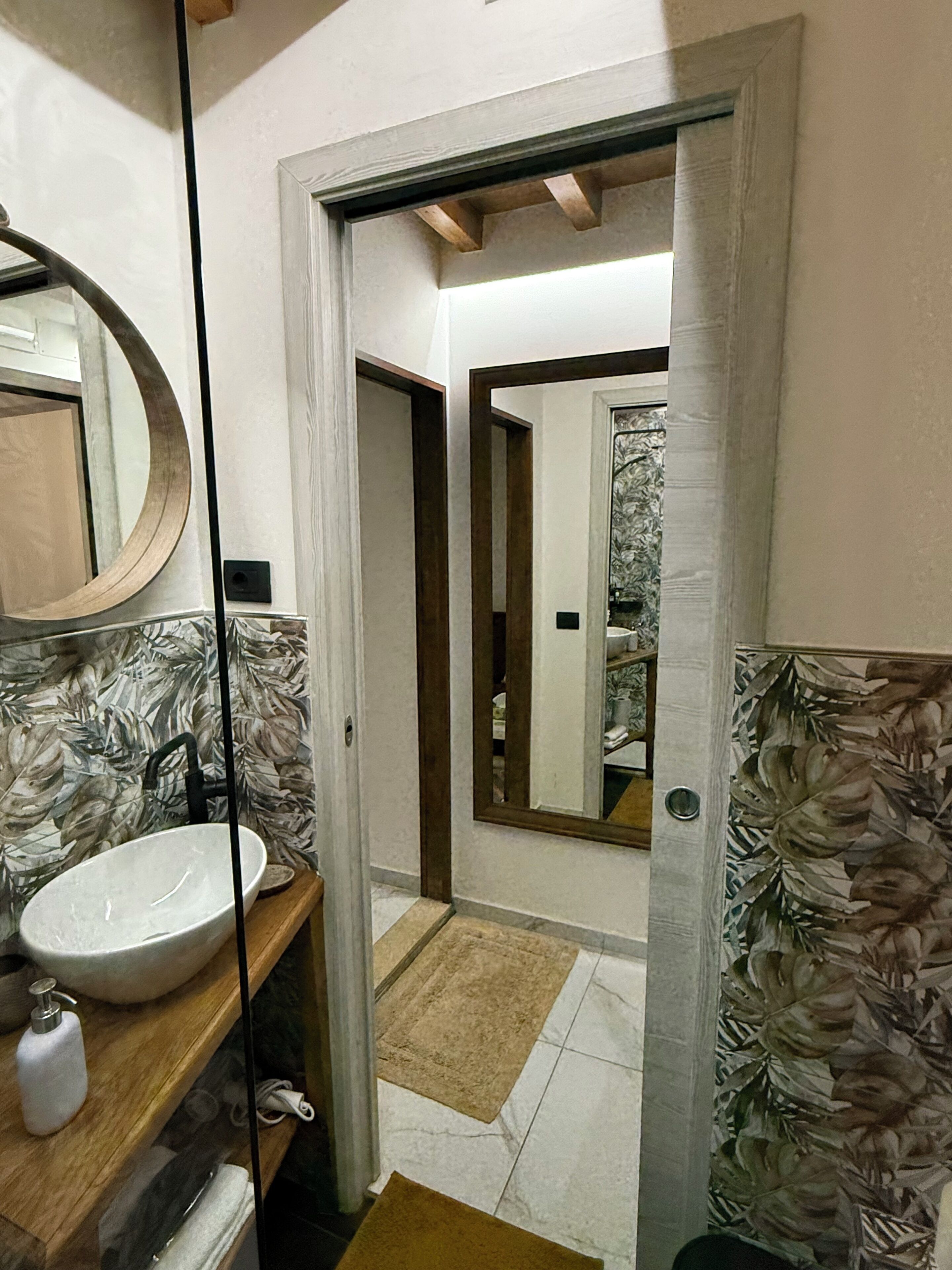 A bathroom with a large mirror, a white sink, and a wooden vanity.