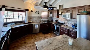 A kitchen with dark wooden cabinets, a stainless steel refrigerator, a microwave, and a stove. - Luxurious Villa " Sea La Vie" in Pelican Key (Koolbaai)