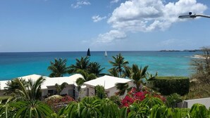 A coastal view with a clear sky, a sailboat, and a building with a white roof. - Luxurious Villa " Sea La Vie" in Pelican Key (Koolbaai)