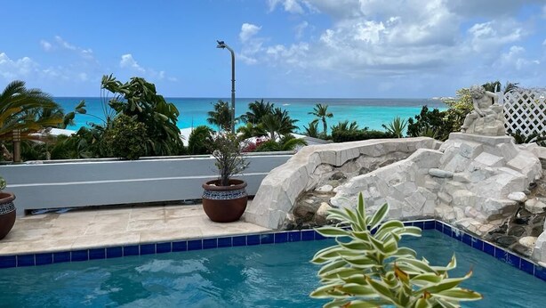 A pool with a view of the ocean, surrounded by rocks and plants. - Luxurious Villa " Sea La Vie" in Pelican Key (Koolbaai)