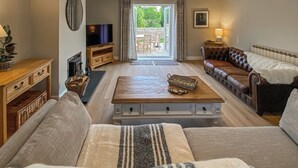 A living room with a sofa, a coffee table, a TV, and a fireplace.