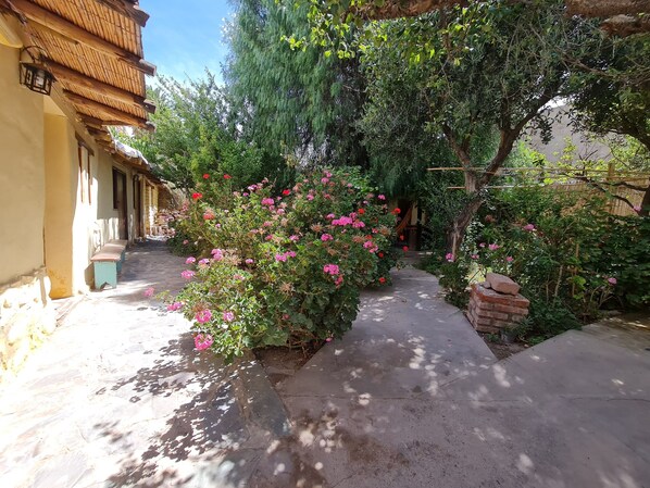 A garden pathway leading to a building with a tiled floor and a bench.