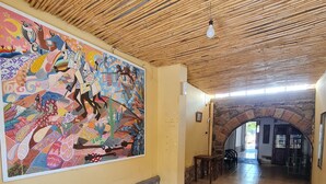 Un pasillo con un mural colorido, paredes de piedra y suelo de baldosas con flechas direccionales.