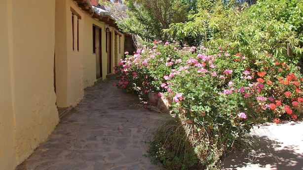 Un sendero de piedra que conduce a un edificio de fachada amarilla y puertas de madera.