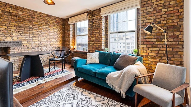 A cozy living room with a brick wall, a teal sofa, a wooden coffee table, and a black floor lamp. - Charming Shoreditch Apartment (London)