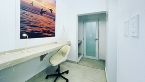 A modern office space with a desk, chair, and a large wall-mounted picture of a sunset over water.