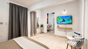 A hotel room with a bed, a TV, a desk, and a chair.