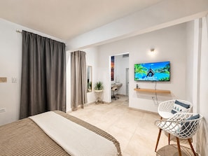 Hotellihuone, jossa on sänky, televisio, työpöytä ja tuoli.