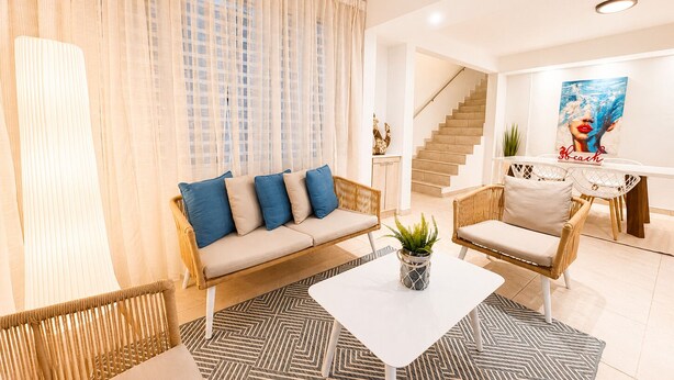 A modern living room with a sofa, chairs, a coffee table, and a staircase.