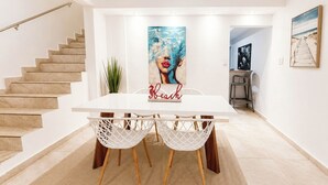 A dining area with a white table, white chairs, and a rug.