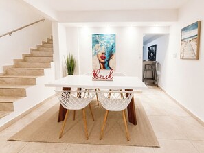Un espace repas avec une table blanche, des chaises blanches et un tapis.