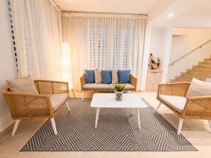 Un salon comprenant un canapé, deux fauteuils, une table basse et un escalier.