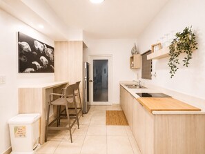A modern kitchen with a wooden countertop, a sink, and a refrigerator. There is a dining area with chairs and a table.