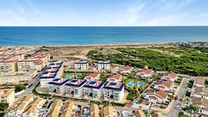 Una zona residencial costera con edificios de varios pisos, una playa y cielo despejado.