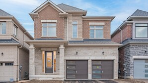 A two-story residential building with a brick facade, two garage doors, and a front entrance with a door number 137. - Luxury Villa 5BR-4.5 Bath (Springwater)