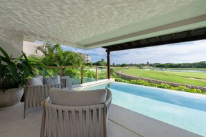 Ein moderner Außenbereich mit Liegebereich, Pool, bequemen Sitzmöglichkeiten und Blick auf Golfplatz und Wasserspektrum.