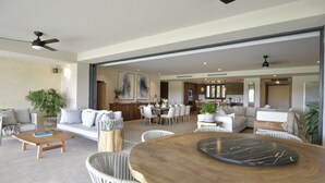 Un vaste espace de vie comprenant une table à manger, des canapés et une cuisine à l’arrière-plan.