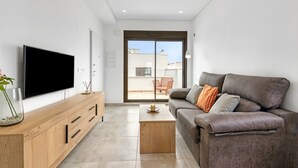 Ein modernes Wohnzimmer mit einem Flachbildfernseher, einer Holz-Entertainment-Möbeln, einem braunen Ledersofa und einer Schiebeglastür zu einem Außenbereich.